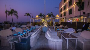 An outdoor dining area with wicker furniture and tables set for dining. - The Nagpur Ashok (Nagpur)