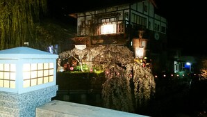 Un bâtiment traditionnel doté d’une façade en pierre et d’un balcon en bois, illuminé par un éclairage chaleureux.