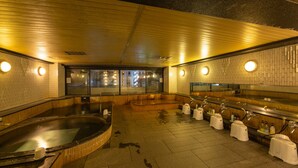 Un sauna doté de plusieurs bains et d’un espace douche séparé, avec des murs carrelés et un plancher en bois.