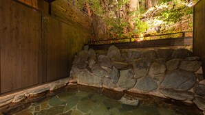 A stone hot spring with a wooden wall and a stone wall surrounding the area. - Merveille Arima (Kobe)