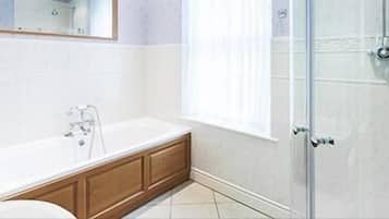 A bathroom with a bathtub, a shower, and a window.