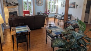 Amplia sala de estar con chimenea, comedor con varias mesas y un gran ventanal con cortinas.