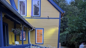 Una casa amarilla con detalles azules y un porche.