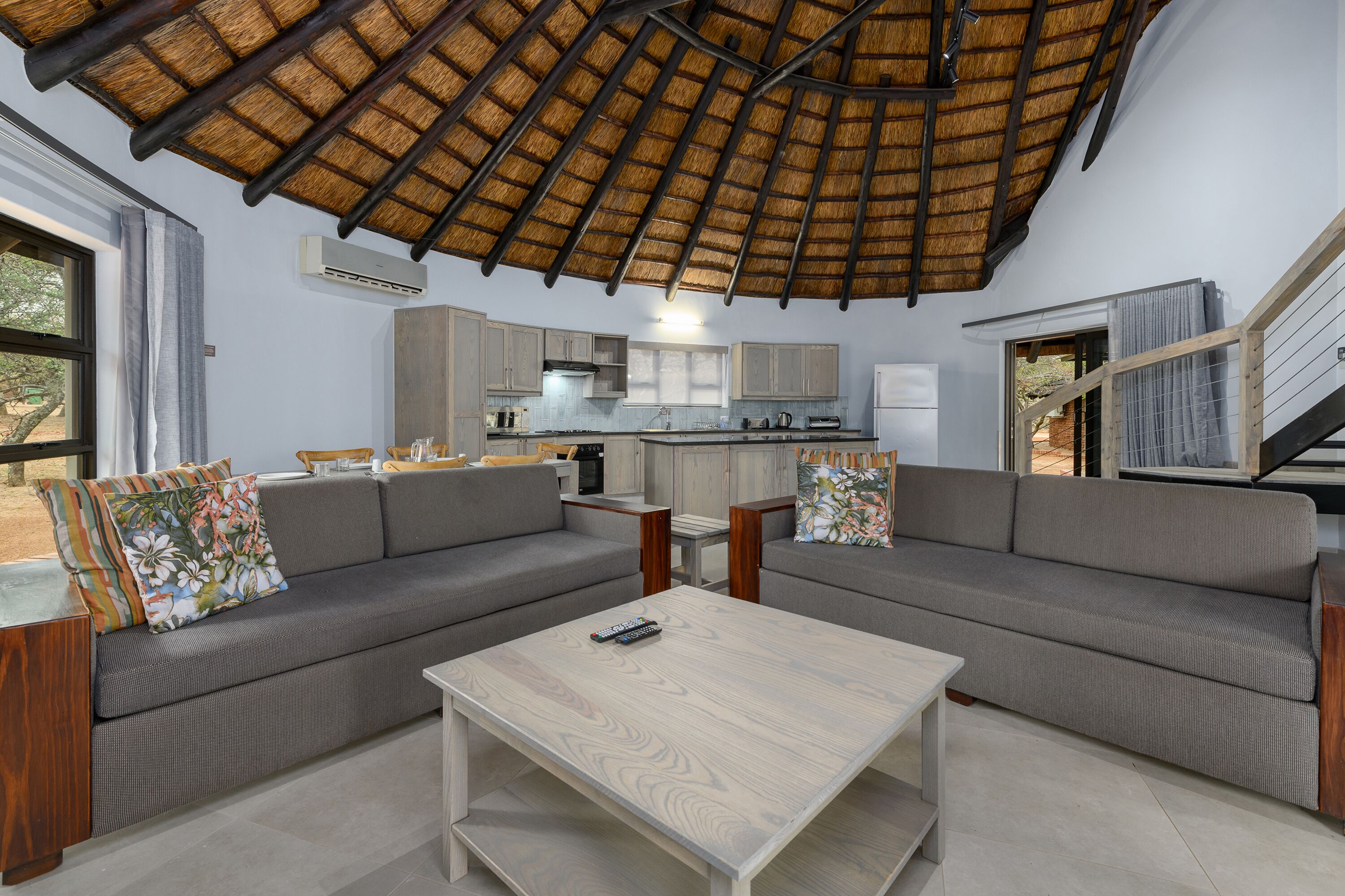 Un salon moderne avec un canapé gris, une table basse en bois et un plafond recouvert de chaume.