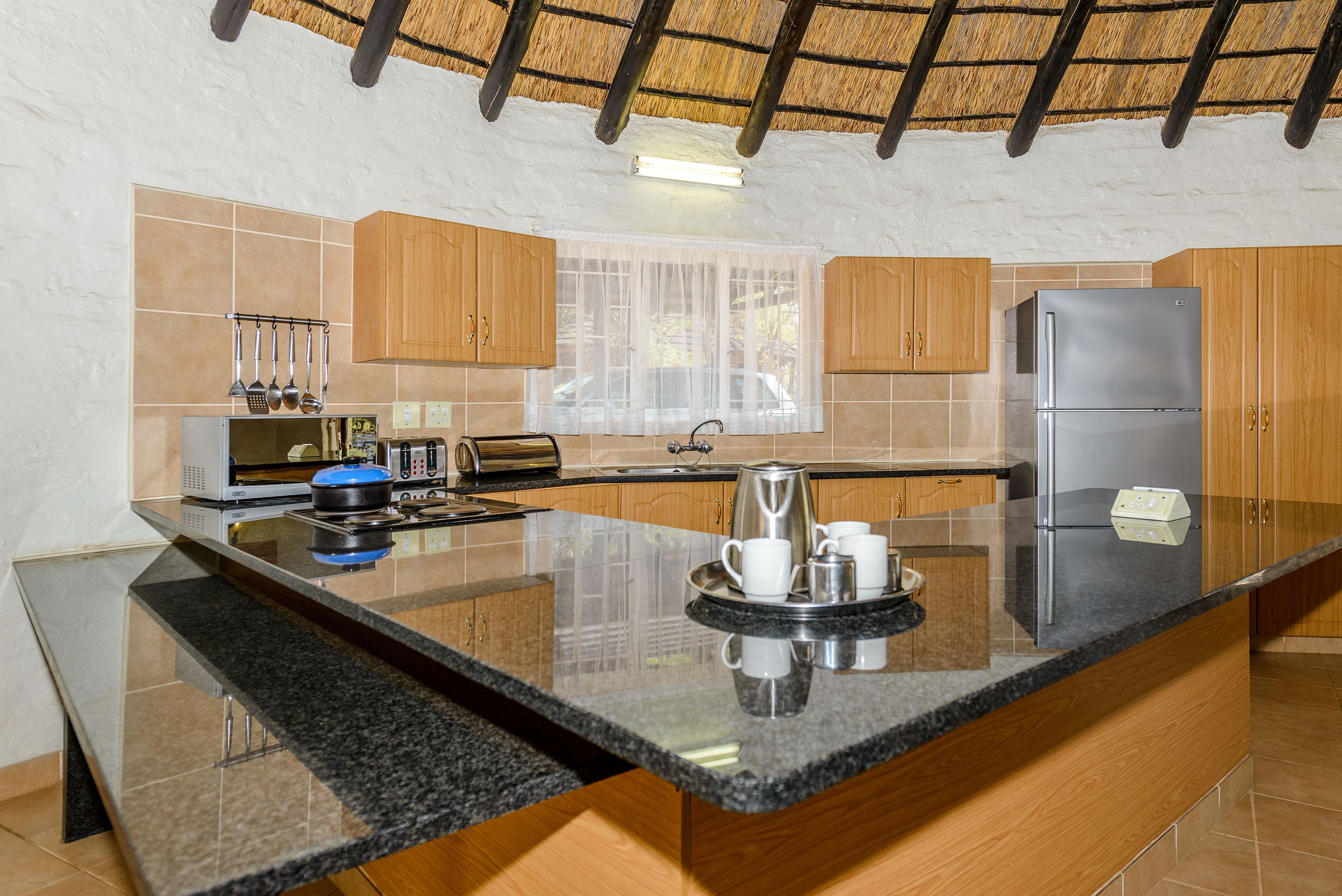 A modern kitchen with wooden cabinets, a stainless steel refrigerator, and a granite countertop.