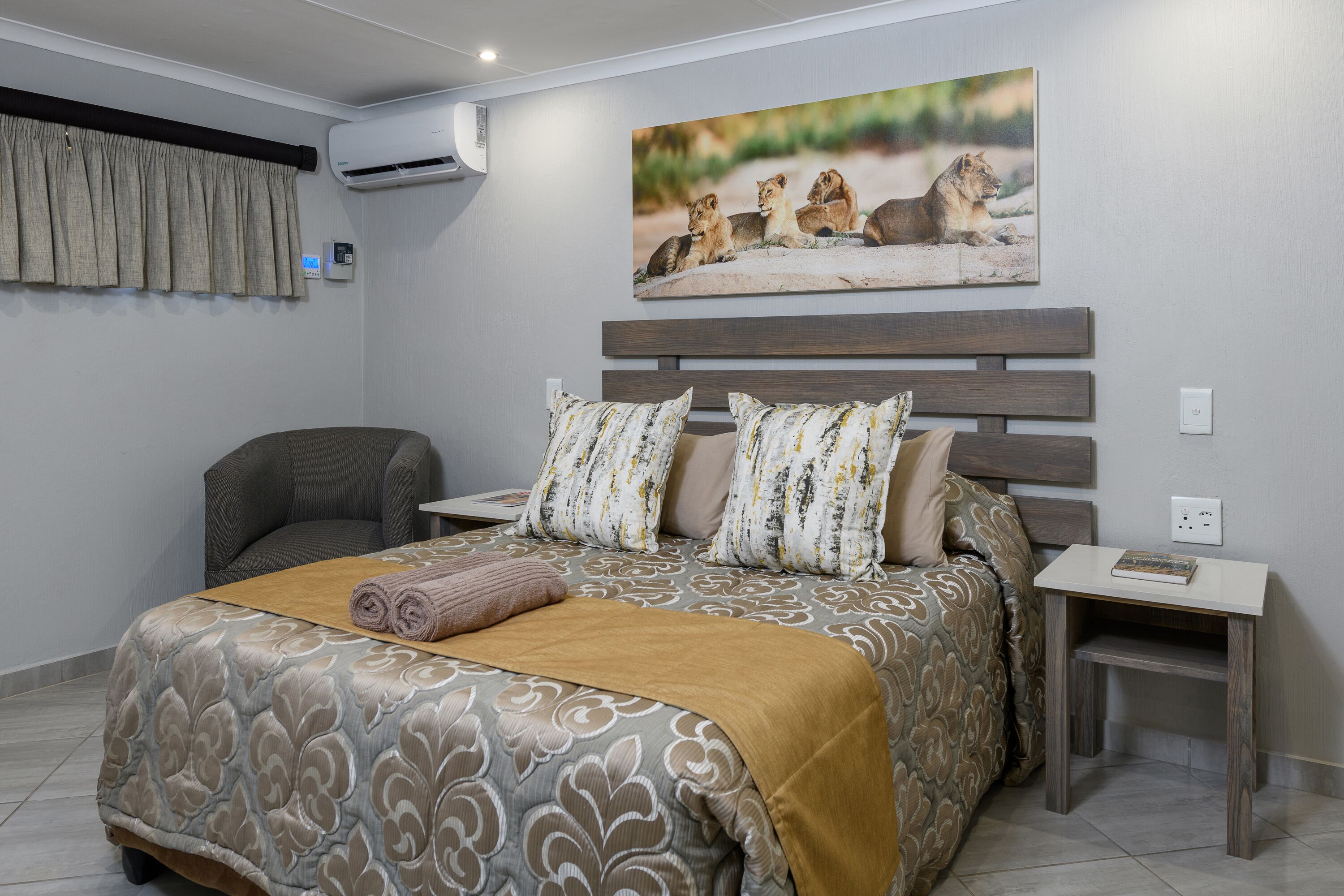 Une chambre à coucher avec un grand lit, une chaise, une table de chevet et un climatiseur fixé au mur.