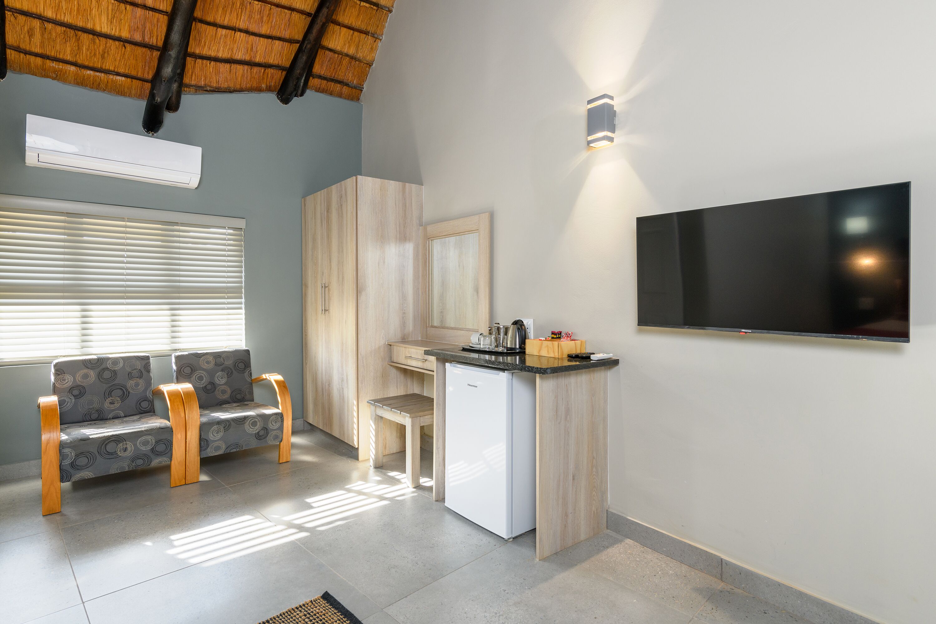 Un espace de vie compact comprenant un coin cuisine, un coin salon avec un canapé et une petite table, ainsi qu’un téléviseur à écran plat fixé au mur.
