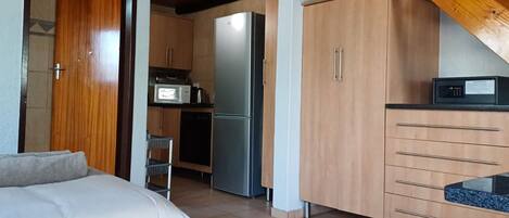 Une chambre d’hôtel compacte comprenant un coin cuisine, un lit et une poutre en bois au plafond.