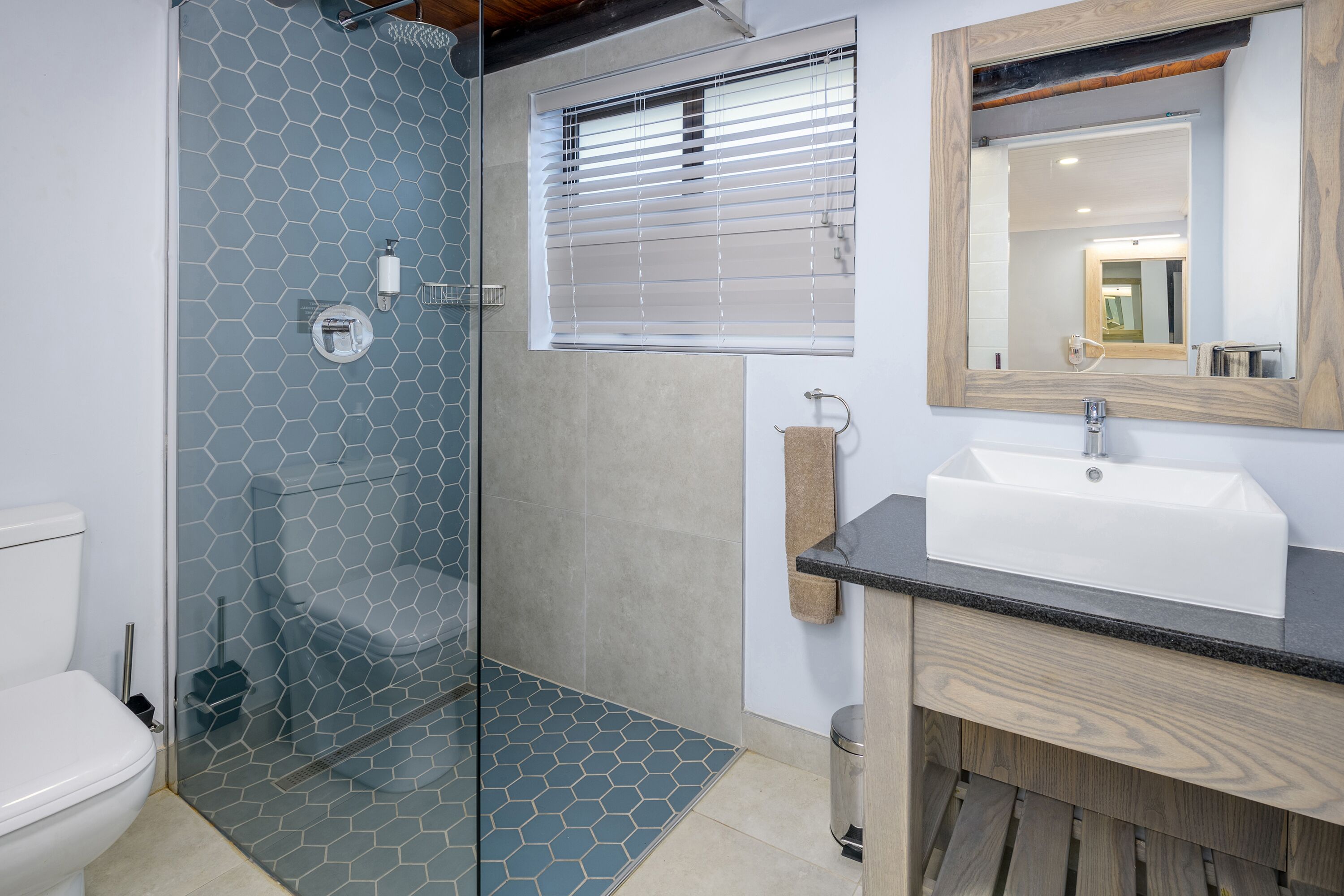 A bathroom with a glass shower enclosure, a white sink, and a wooden vanity.