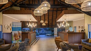 Un hall d'entrée avec des meubles en osier, un comptoir de réception et des luminaires suspendus.
