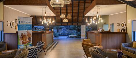 A lobby with wicker furniture, a reception desk, and hanging light fixtures.