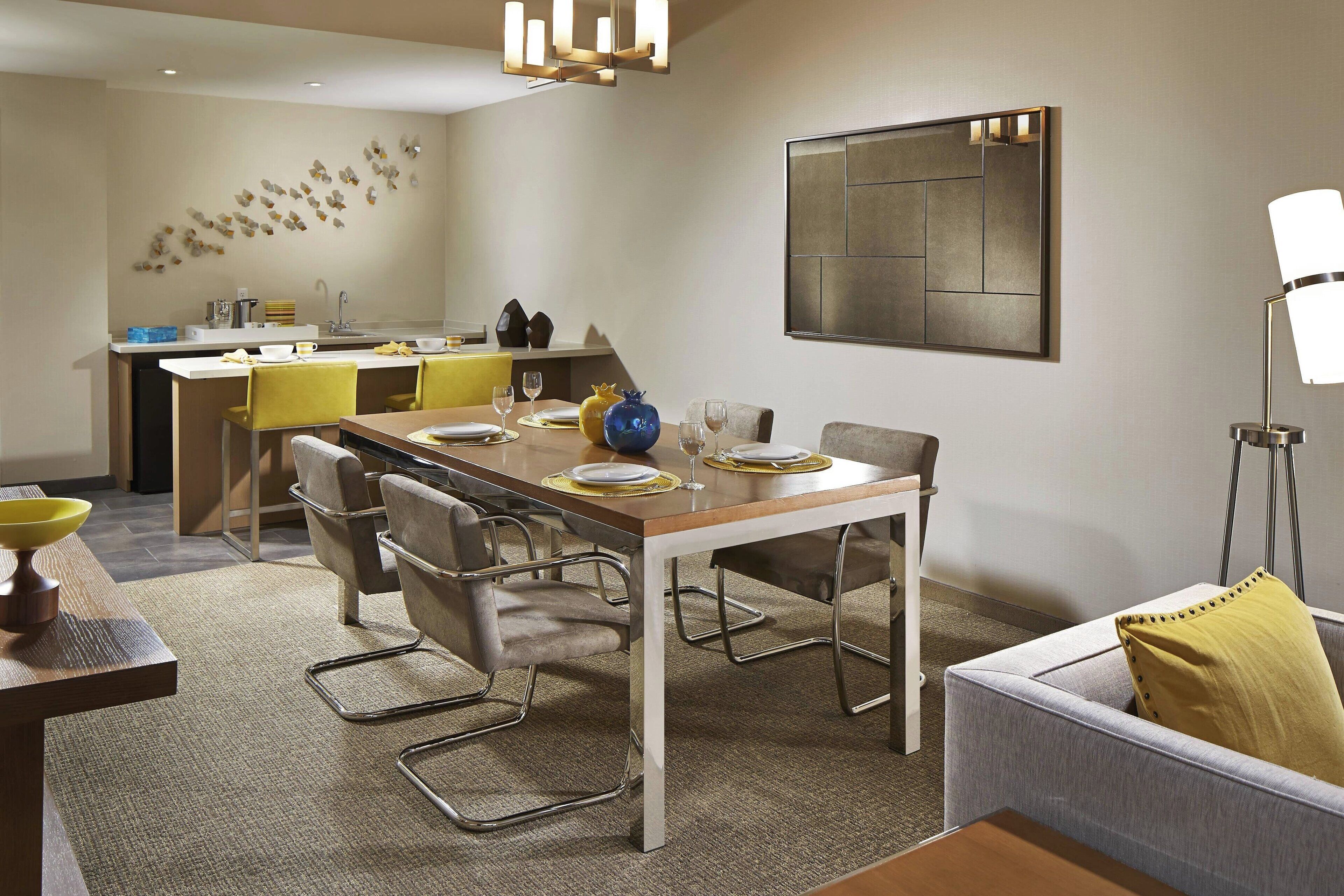 Un espace repas moderne avec une table en bois, des chaises en métal et un canapé gris.