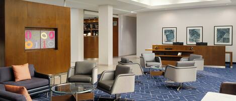 A modern lobby with seating areas, a reception desk, and artwork on the walls.
