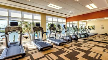 Un gimnasio con cintas de correr, elípticas y una amplia pared de espejos.