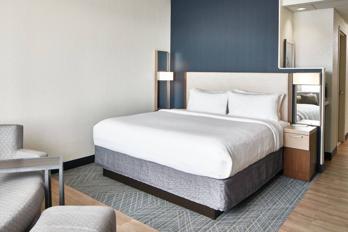 A hotel room with a bed, bedside tables, a chair, and a small table.