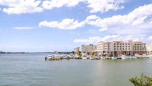 A marina with several boats docked, a hotel with multiple floors and balconies, and a clear sky with scattered clouds. - Courtyard St. Petersburg Clearwater/Madeira Beach (Madeira Beach)