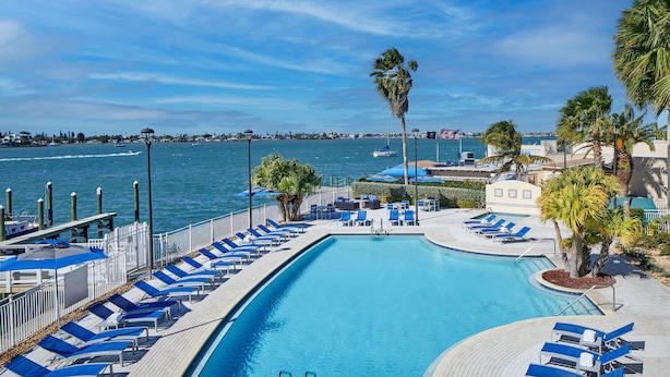 A pool with blue lounge chairs and a view of the water. - Courtyard St. Petersburg Clearwater/Madeira Beach (Madeira Beach)