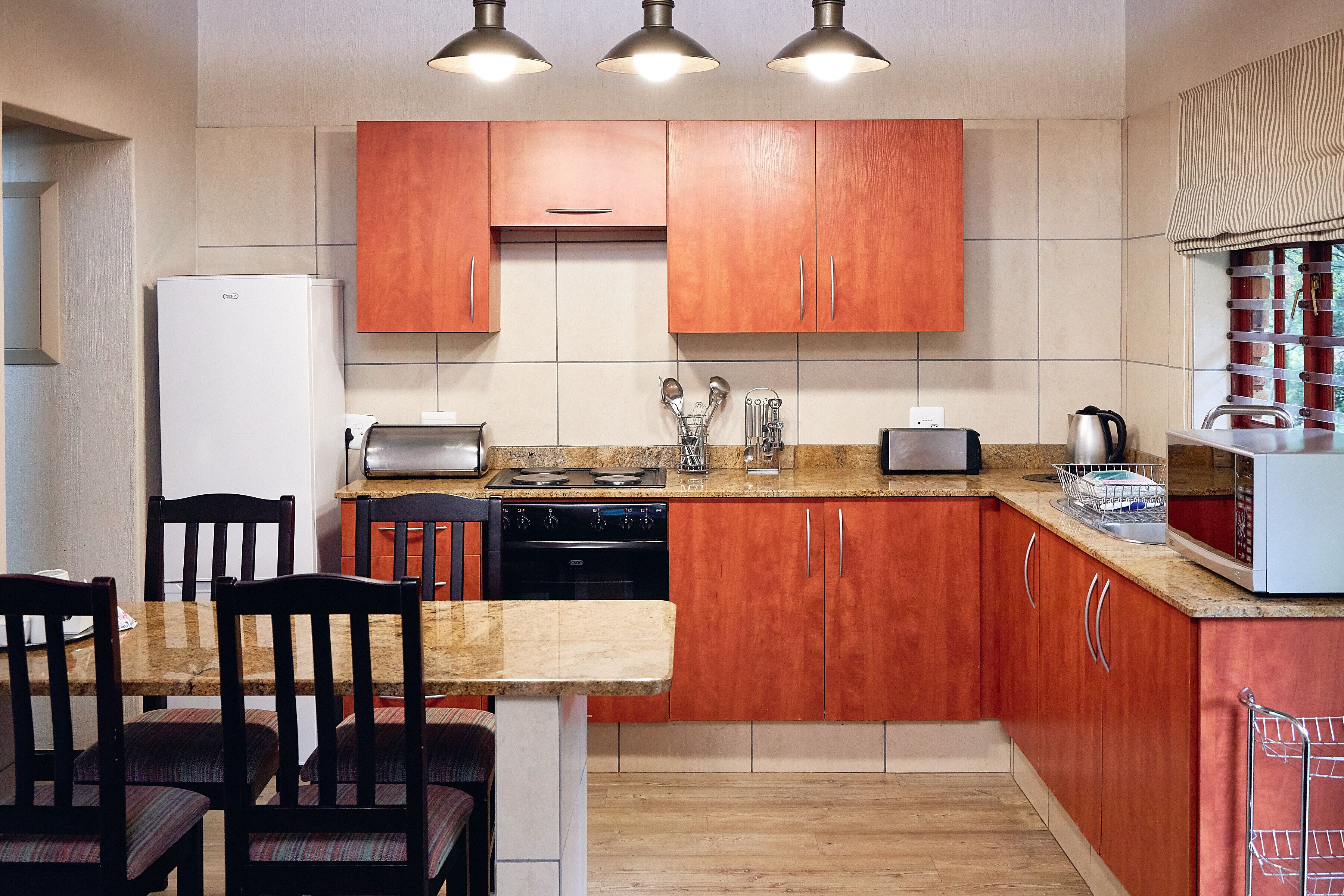 Een keuken met houten kastjes, een granieten aanrecht, een fornuis en een koelkast.
