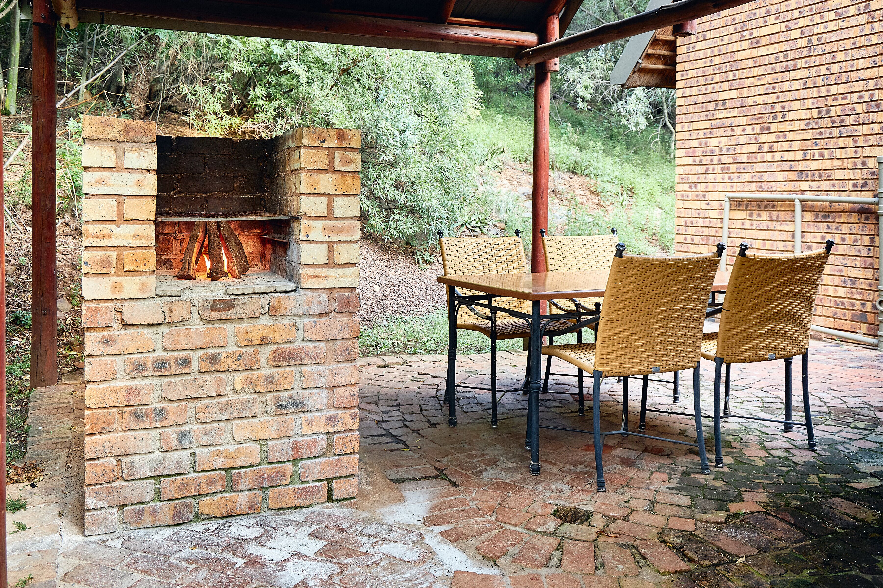 Un horno de ladrillo al aire libre con una mesa y sillas debajo.