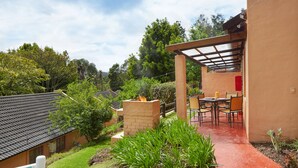 Un patio con una chimenea de ladrillo, mobiliario exterior y vistas a casas vecinas.