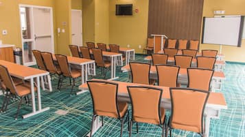 Una sala de conferències amb taules i cadires, una pissarra i una televisió penjada a la paret.