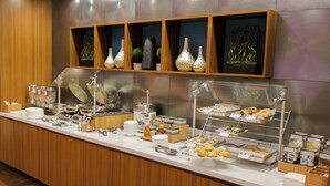 A buffet counter with various food items and a display of decorative vases. - SpringHill Suites Sumter (Sumter)