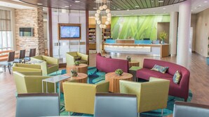A modern lobby with a reception desk, comfortable seating areas, and a large screen TV. - SpringHill Suites Sumter (Sumter)