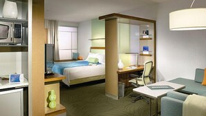 A hotel room with a bed, desk, chair, and a small kitchenette area with a microwave and a refrigerator. - SpringHill Suites Sumter (Sumter)