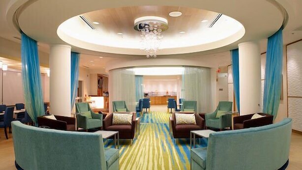 A hotel lobby with a central seating area, a reception desk, and a chandelier. - SpringHill Suites Sumter (Sumter)