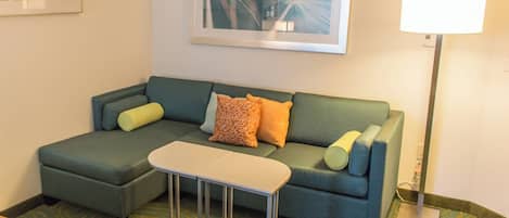 A modern living room with a sectional sofa, a small table, and a floor lamp.