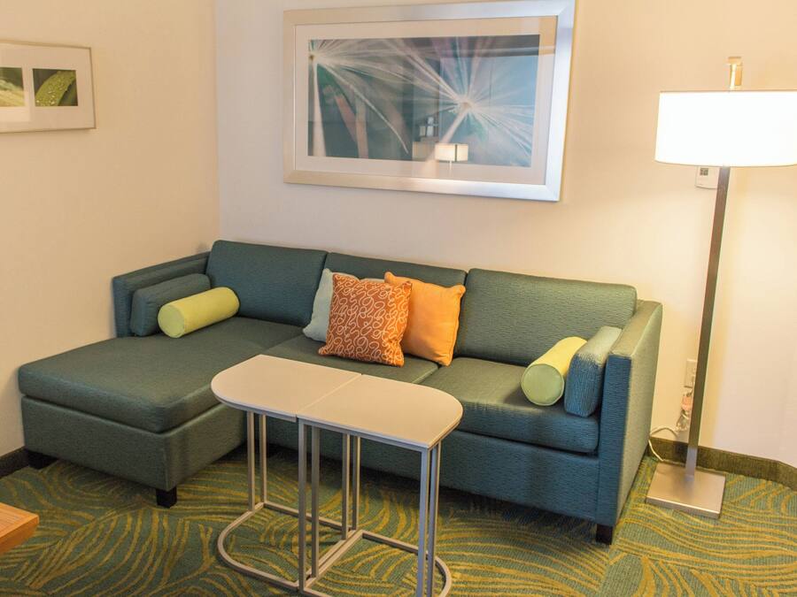 A modern living room with a sectional sofa, a small table, and a floor lamp.