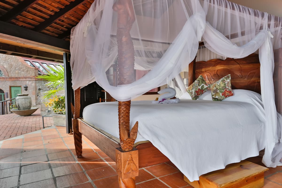 A bed with a wooden headboard, white bedding, and a canopy.