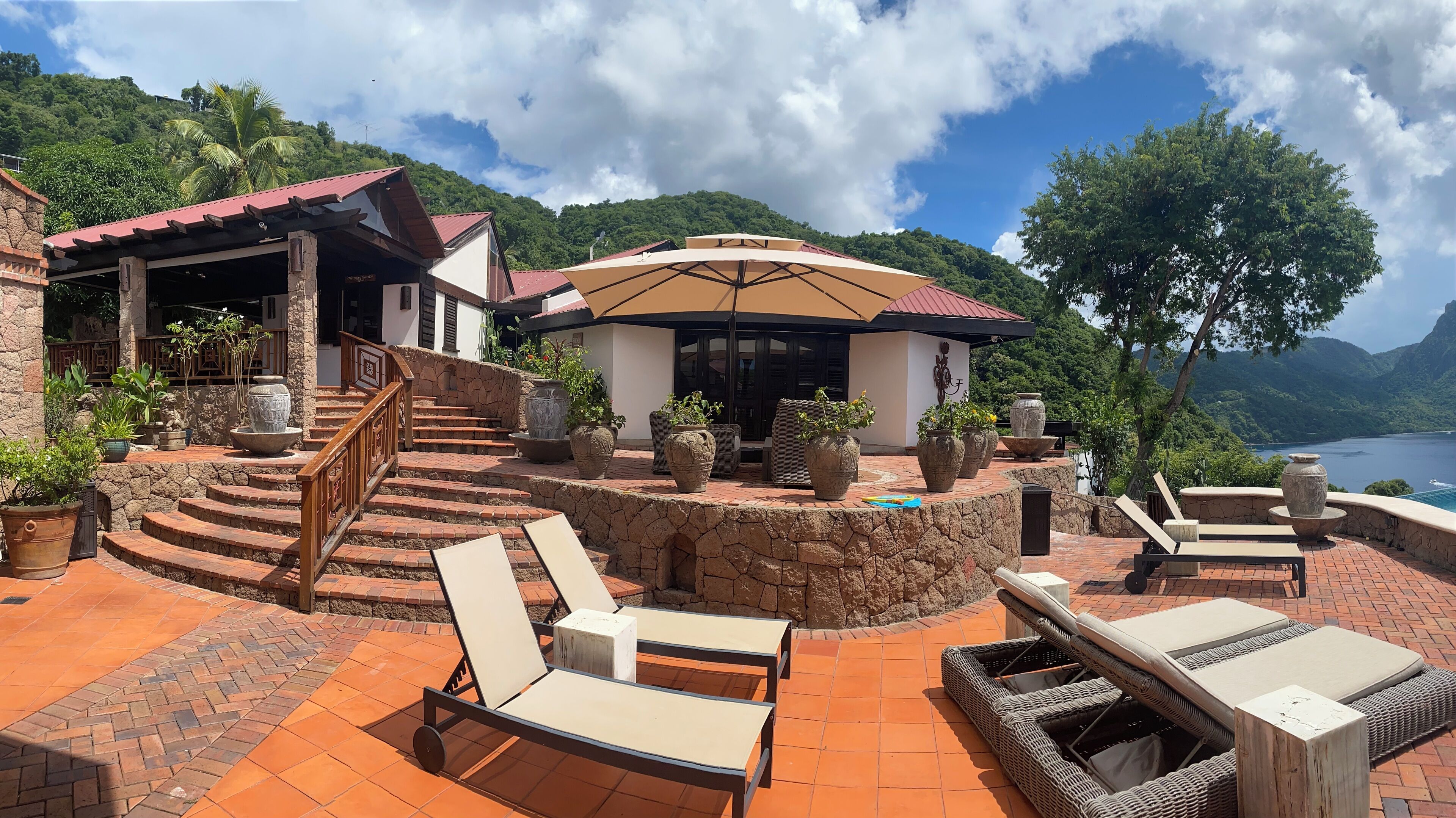 Un resort con una escalera de piedra que lleva a un espacio cubierto con mobiliario para exteriores.