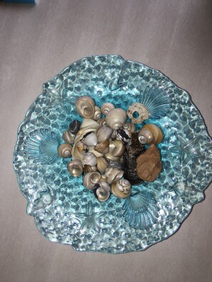 A decorative glass plate with a scalloped edge, featuring a collection of seashells and starfish.