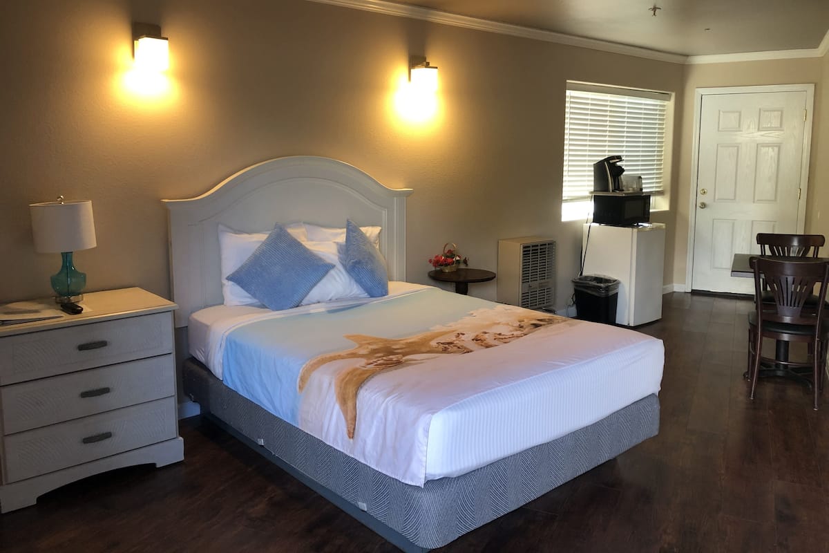 A bedroom with a bed, bedside tables, a lamp, a TV, and a door.