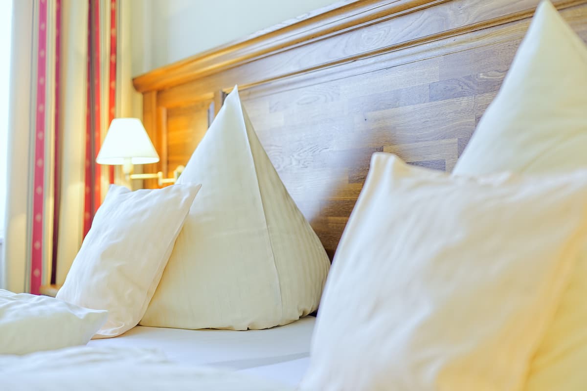 A bed with white pillows and a wooden headboard.