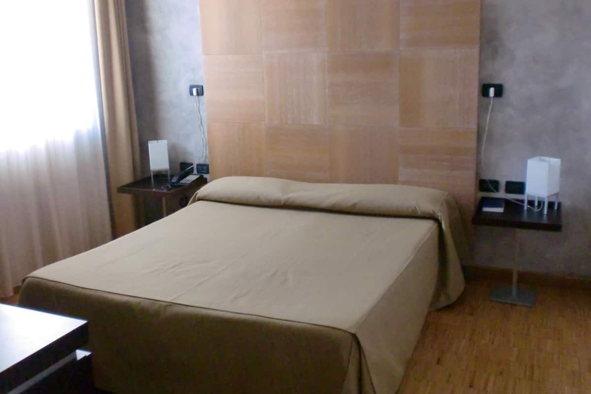 Una habitación de hotel con una cama grande, un escritorio y dos mesitas de noche con lámparas.