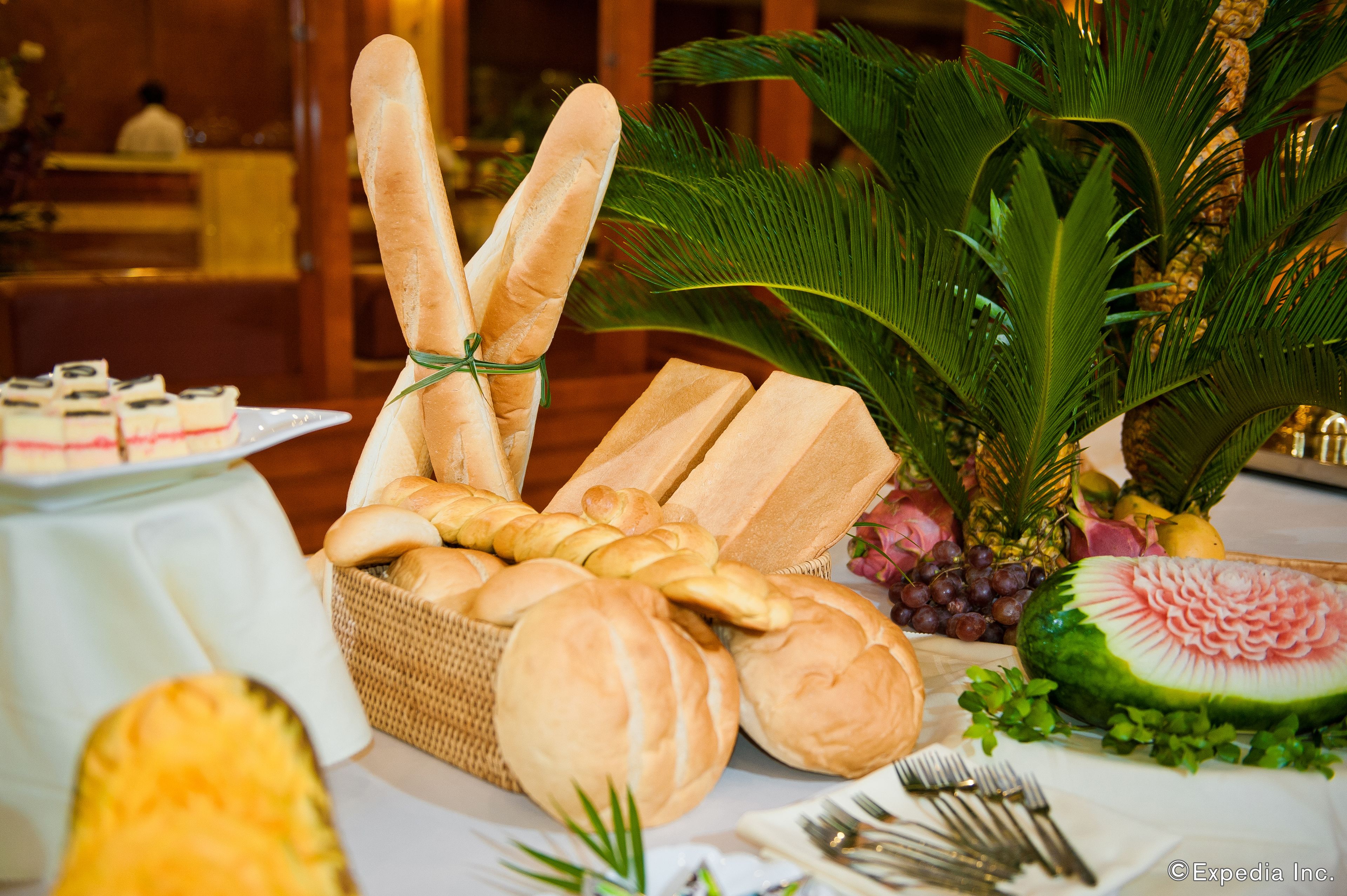 Una mesa de buffet con panes variados, una sandía y una cesta de mimbre.