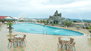 Una piscina al aire libre, sombrillas, sillones reclinables de piscina