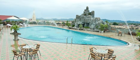 Una piscina al aire libre, sombrillas, sillones reclinables de piscina