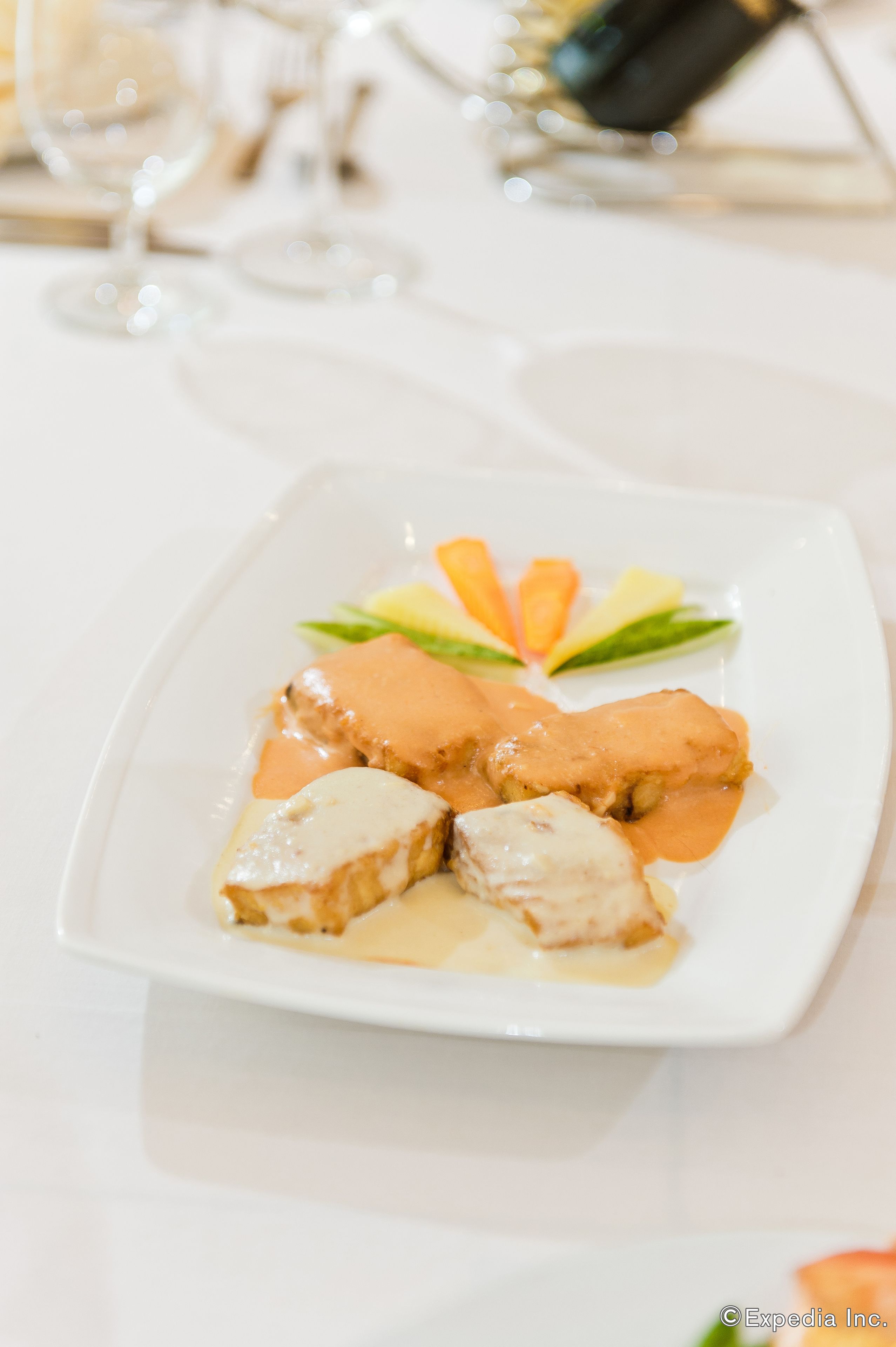 Un plato blanco con comida, un vaso y una botella sobre una mesa.
