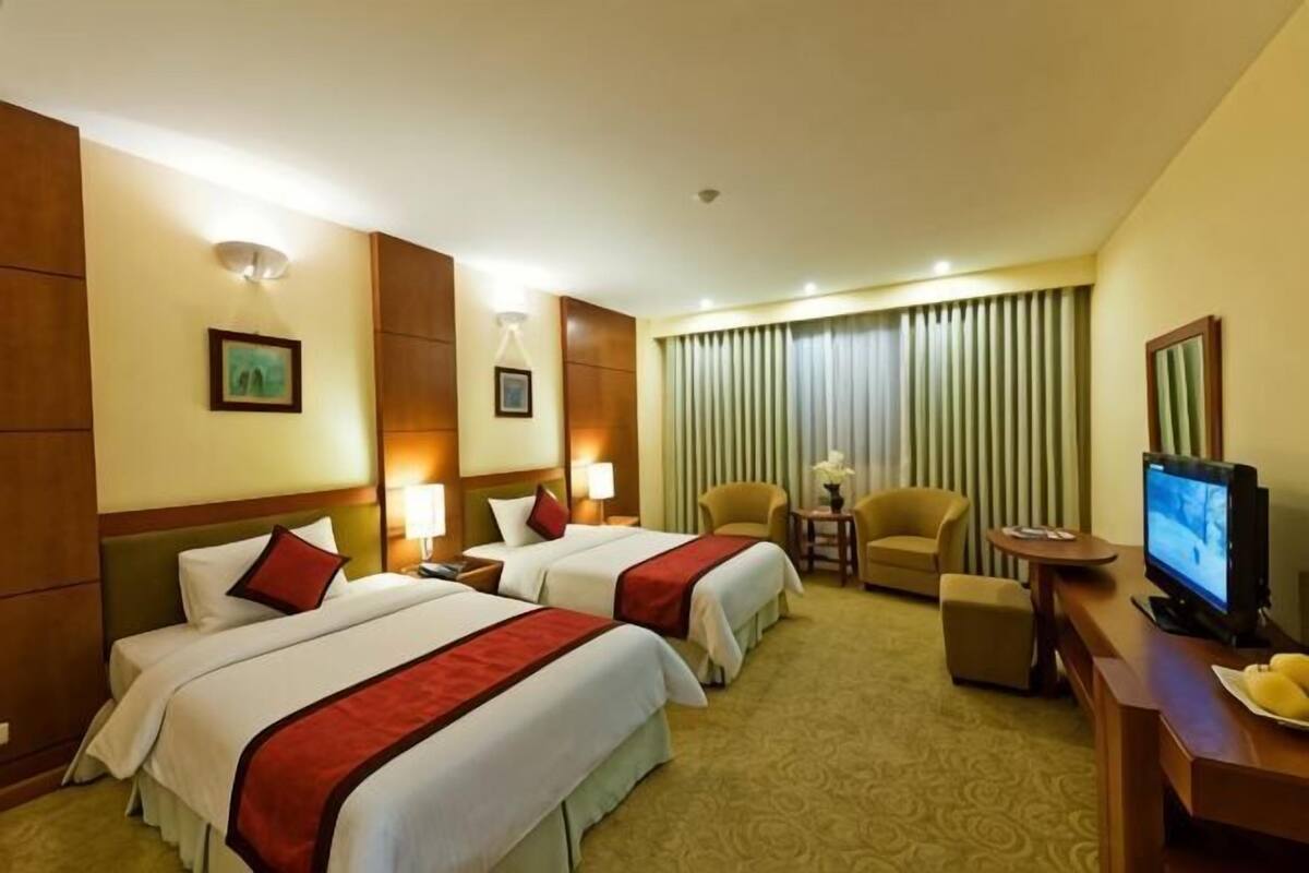 A hotel room with two beds, a TV, a desk, and a chair.
