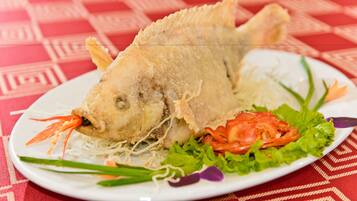 Un plato con pescado frito, lechuga y rodajas de tomate.