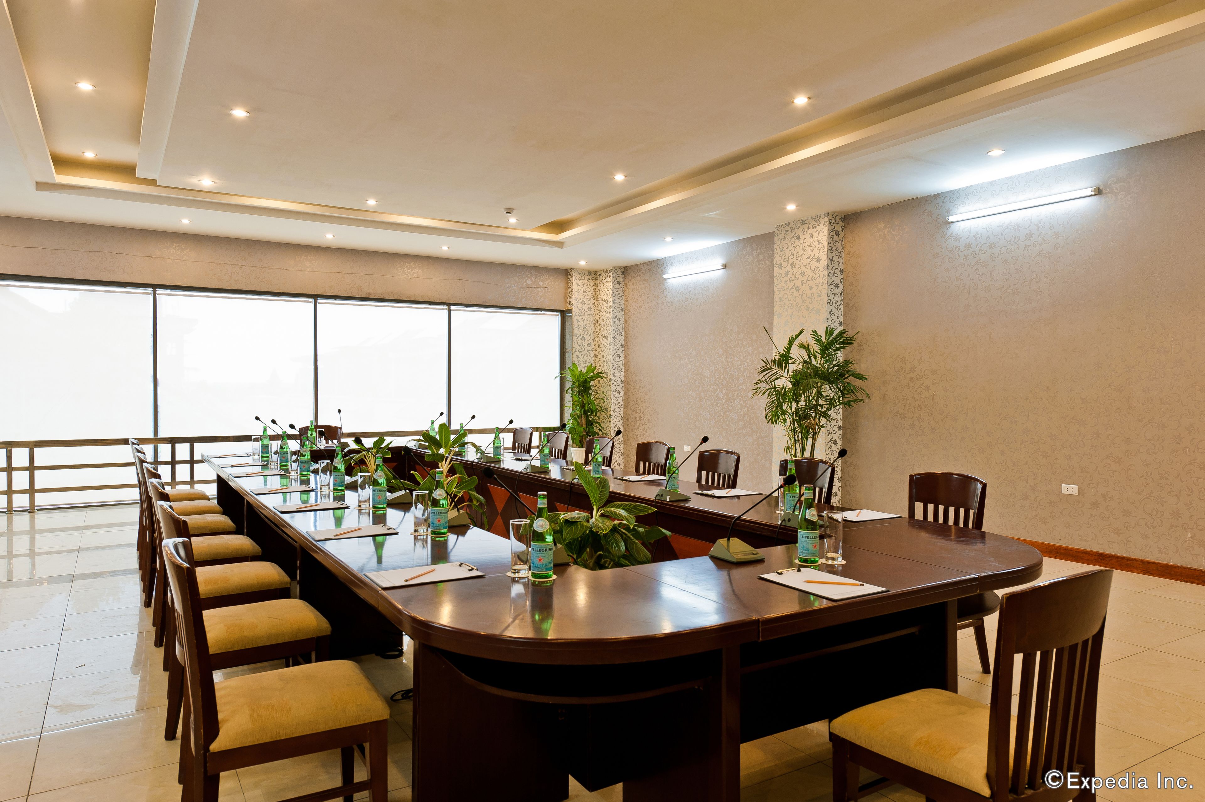 A conference room with a long table, chairs, and potted plants.