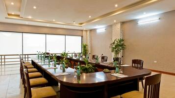 A conference room with a long table, chairs, and potted plants.