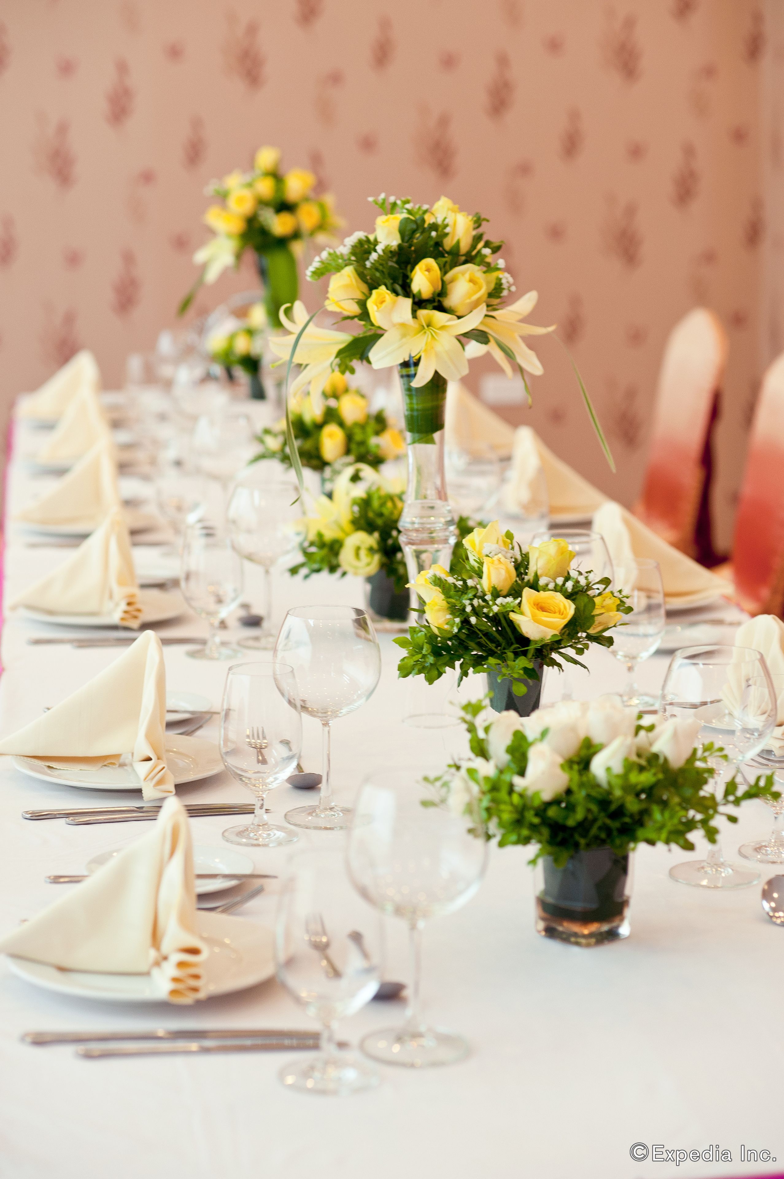A long dining table set with white tablecloths, neatly folded napkins, and clear glassware.