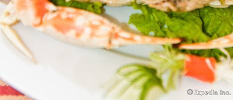 A plate of cooked crabs with green lettuce and red bell peppers.
