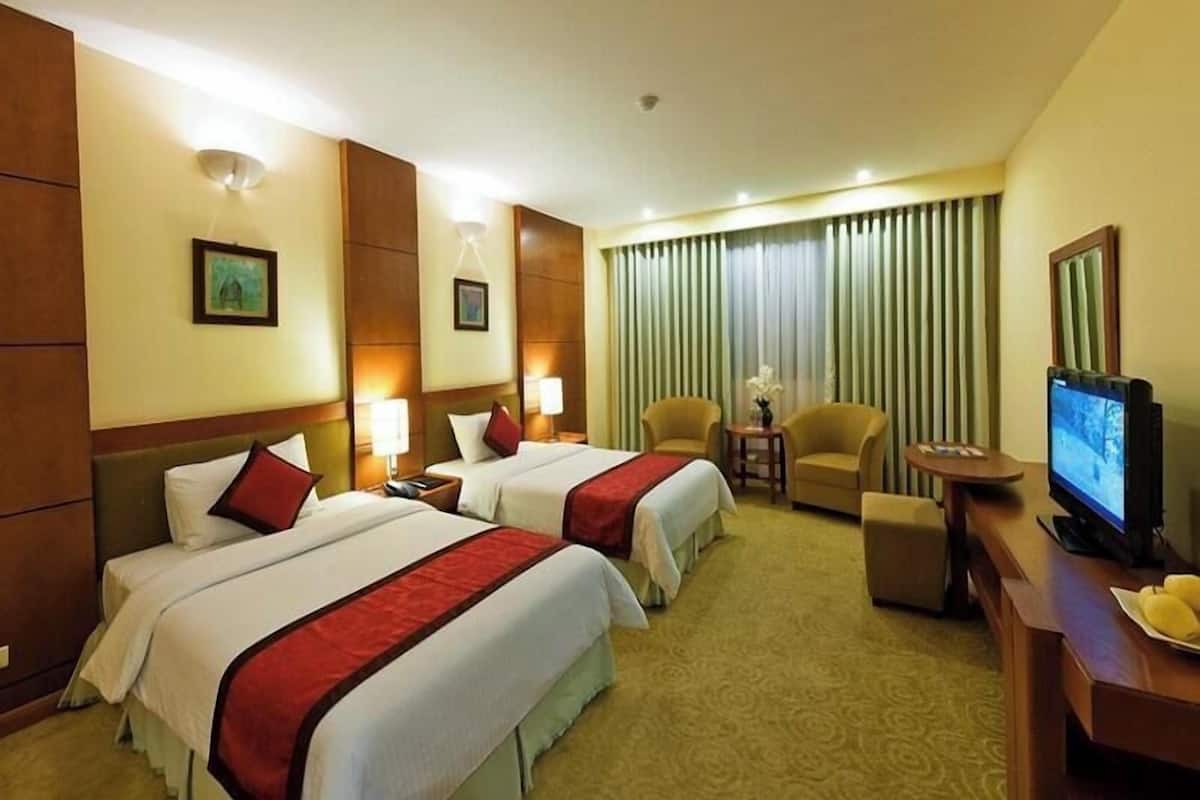 A hotel room with two beds, a TV, a desk, and a chair.