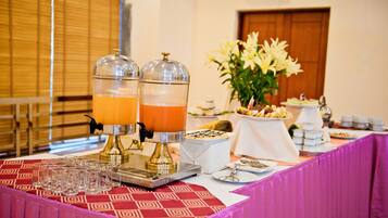 Una mesa de buffet con dos dispensadores de bebidas, diversas opciones de comida y un centro de mesa floral.