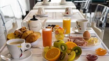 Una mesa con cruasanes, fruta, jugo, café y huevos para el desayuno.